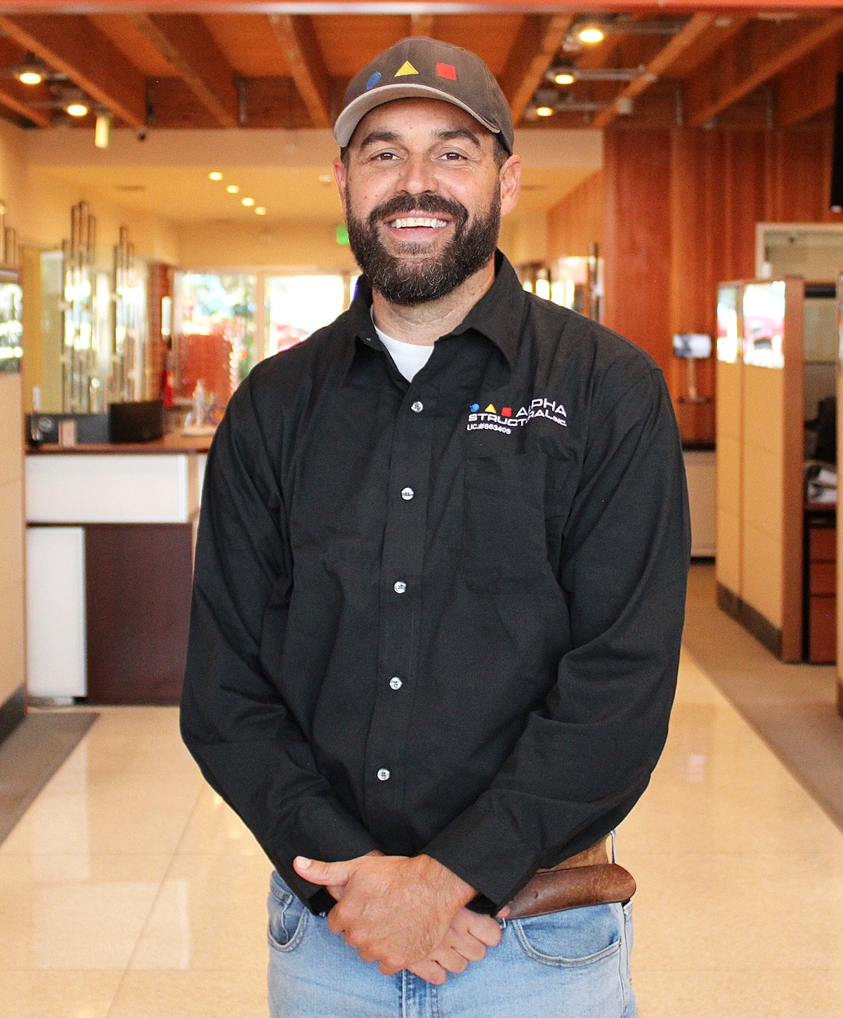 Smiling man in a black shirt, standing indoors.