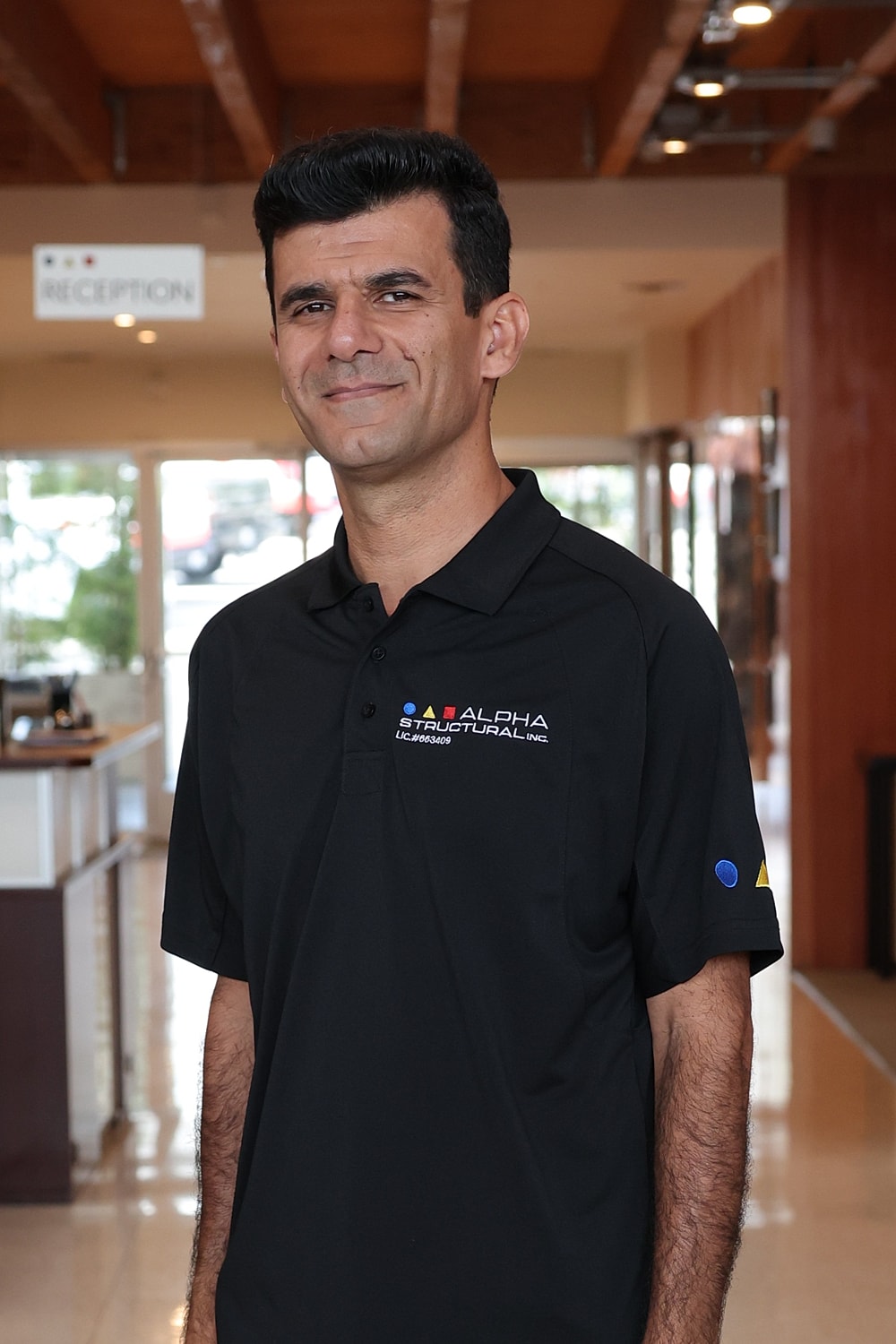 Man standing in reception area wearing company polo.