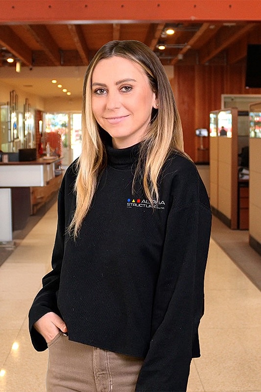 Woman in a black sweater indoors smiling.