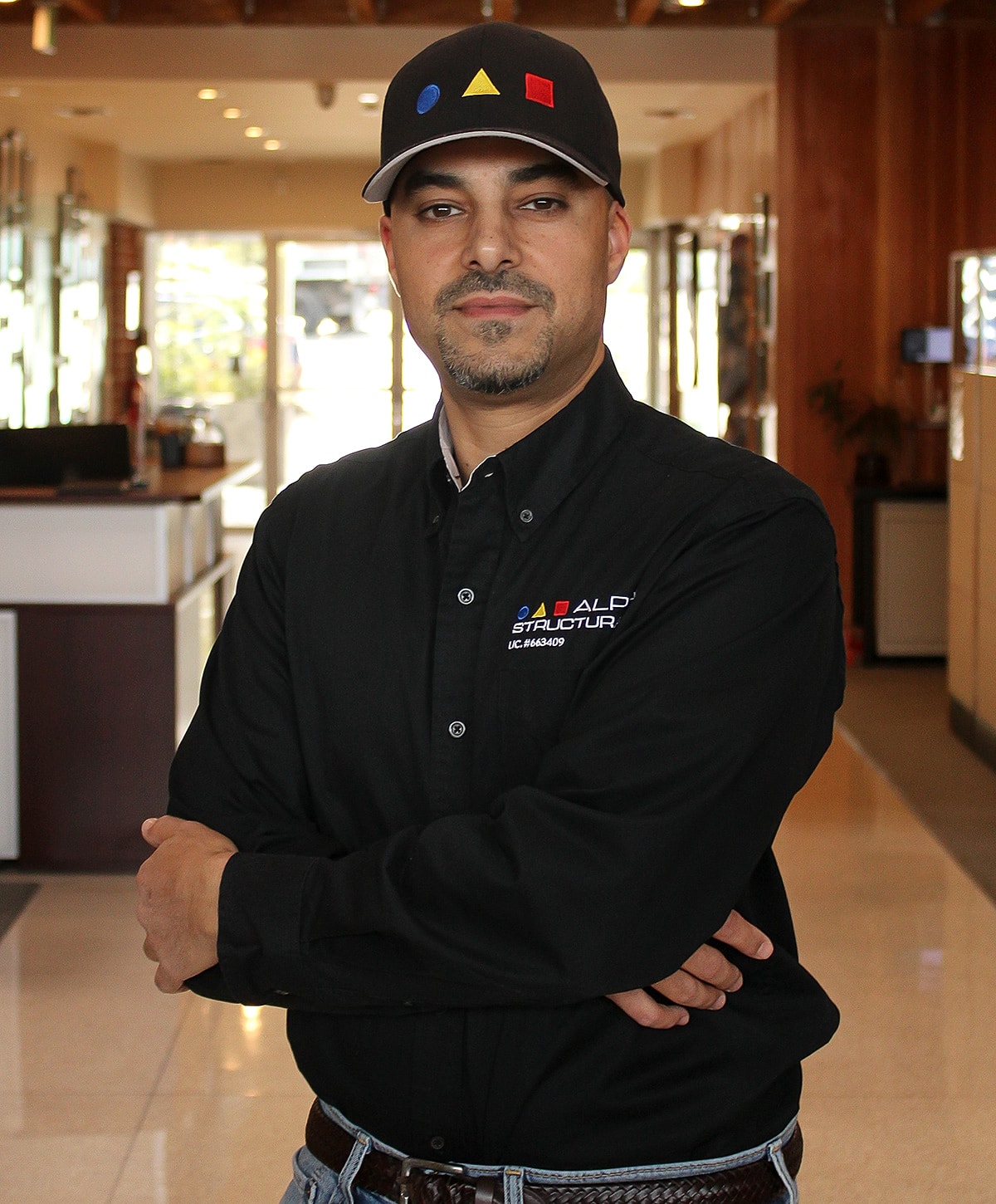 Man in black shirt and cap posing confidently.