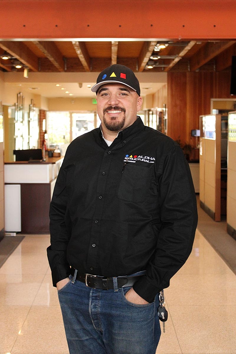 Man in button-up shirt smiling indoors.