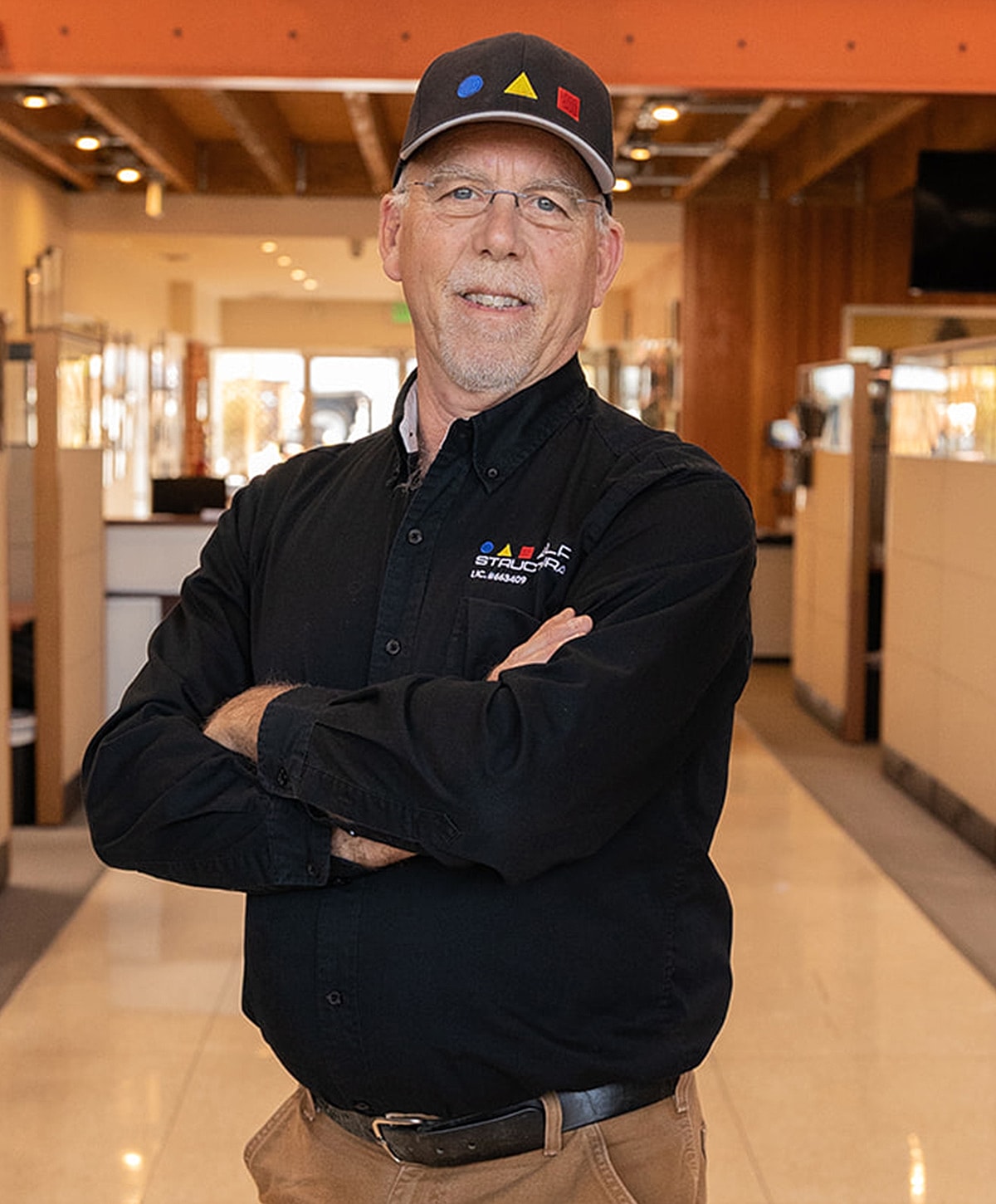 Man in a cap smiling with arms crossed.