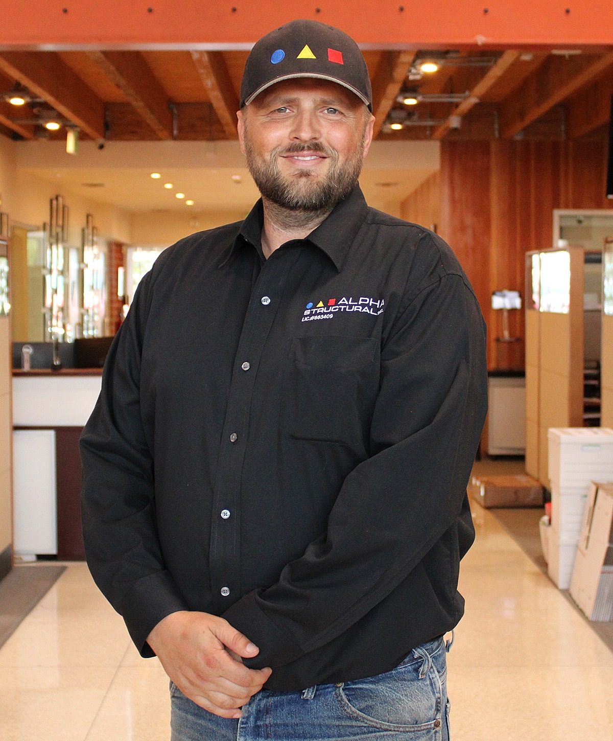 Man in black shirt and cap, indoor setting.