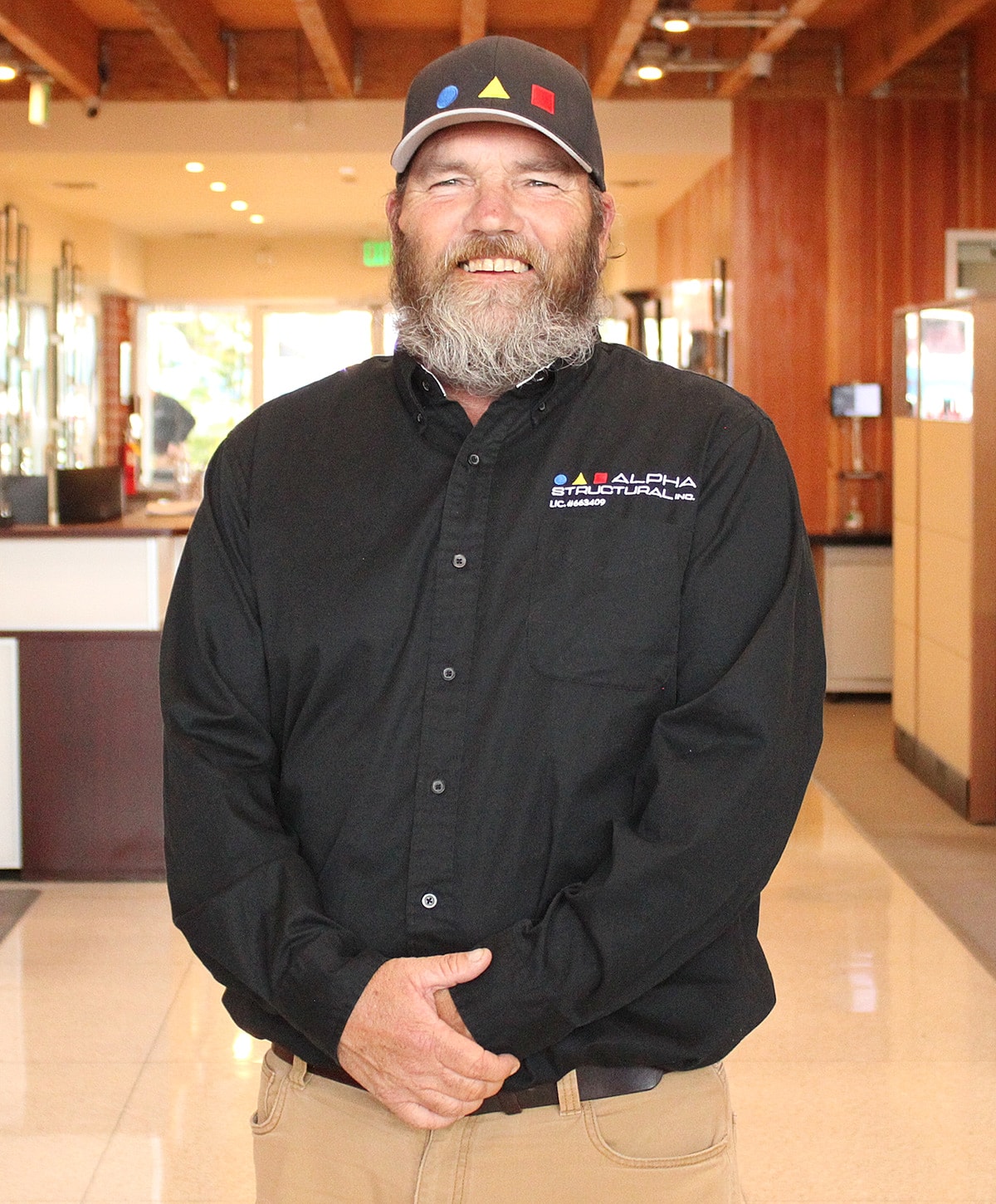 Man smiling in branded work attire indoors.