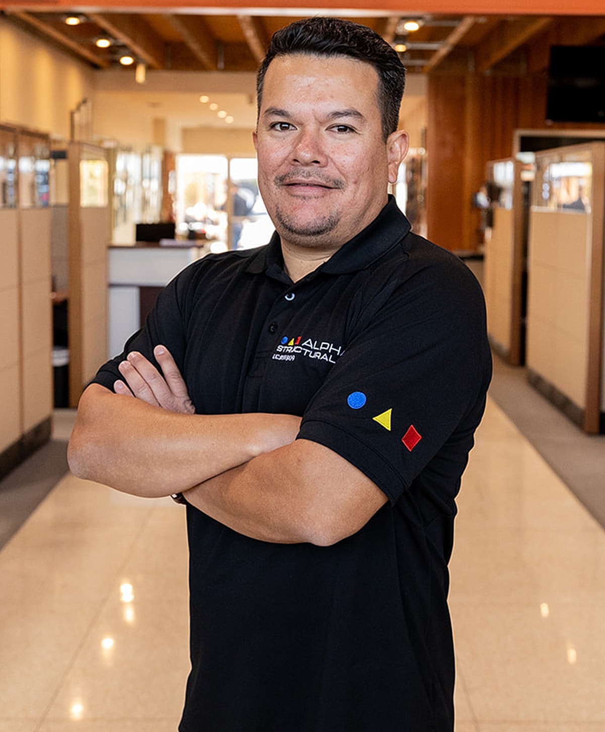 Man in black polo shirt with crossed arms.