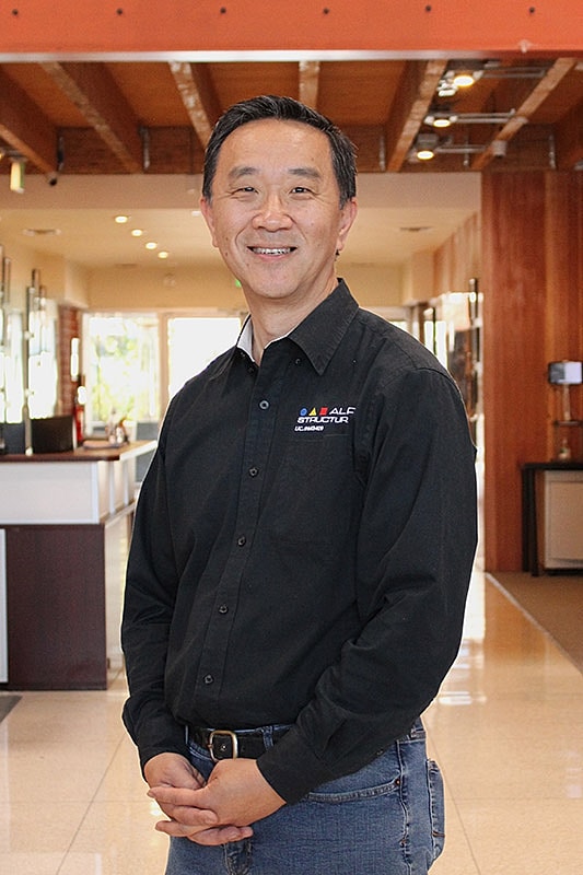 Smiling man in professional setting, black shirt.