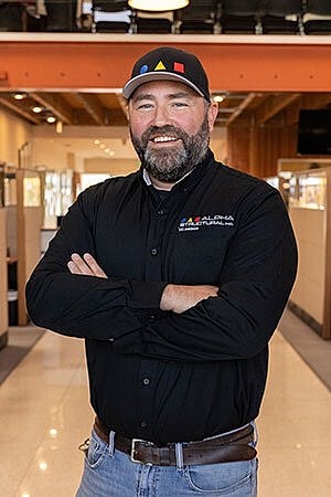 Man in a black shirt smiling confidently indoors.