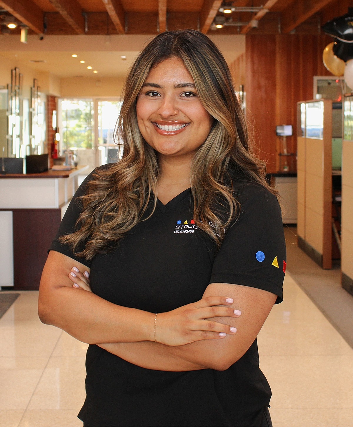 Smiling woman in professional polo shirt, arms crossed.