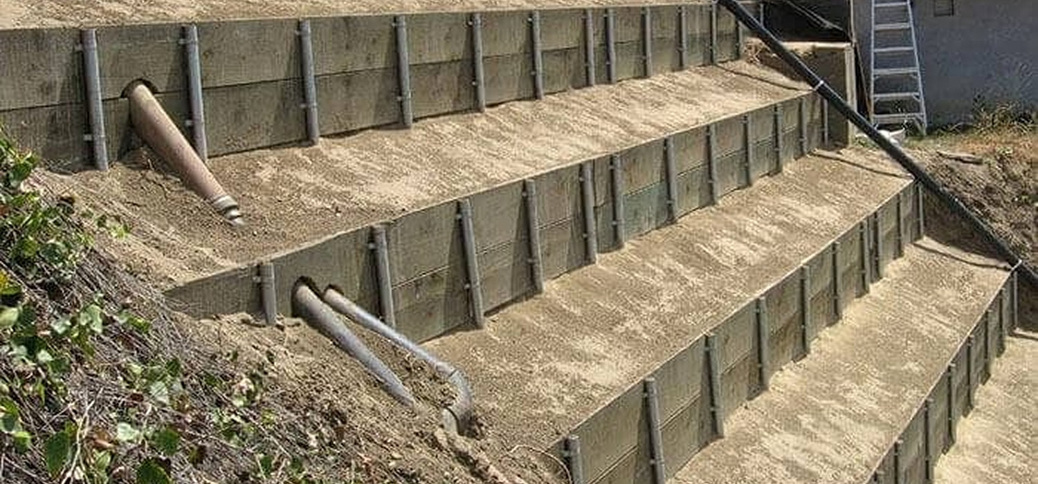 Retaining wall with drainage pipes on slope.