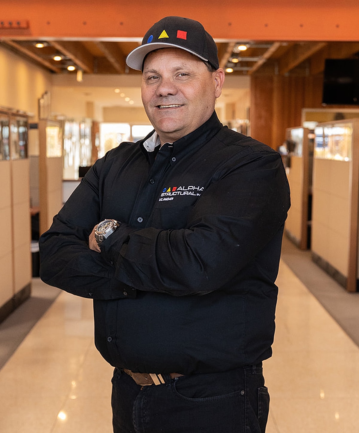 Man in black shirt and cap, smiling confidently.