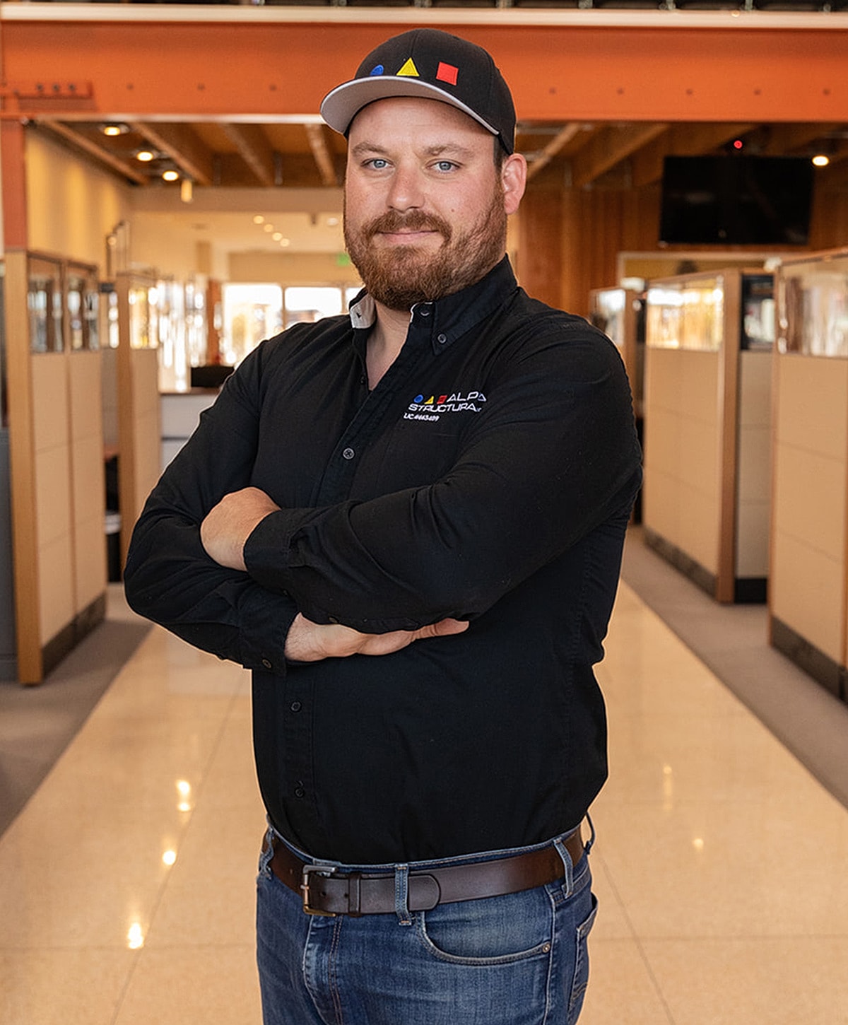 Man in black shirt and cap, arms crossed.
