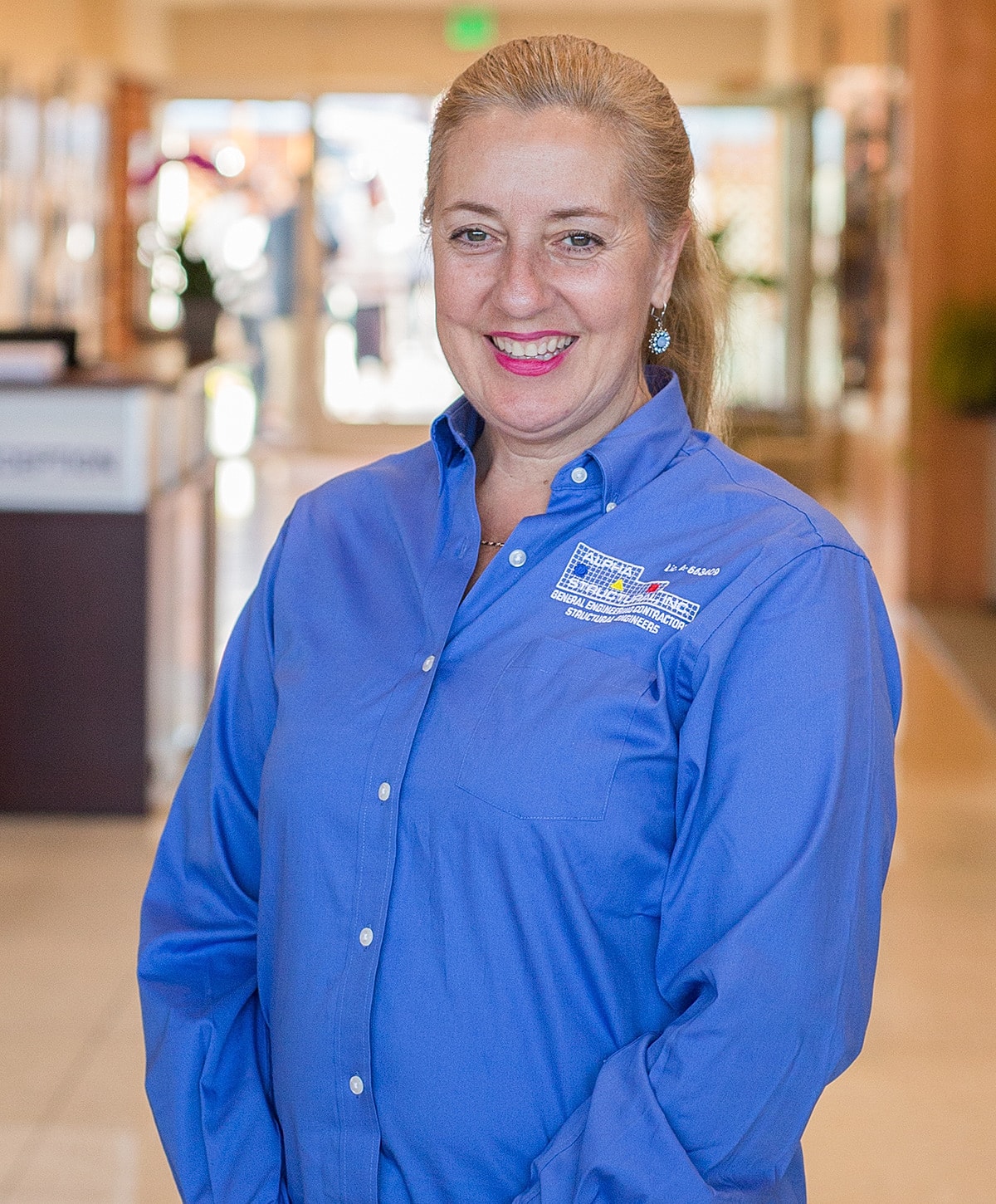 Smiling woman in blue shirt, indoor setting.