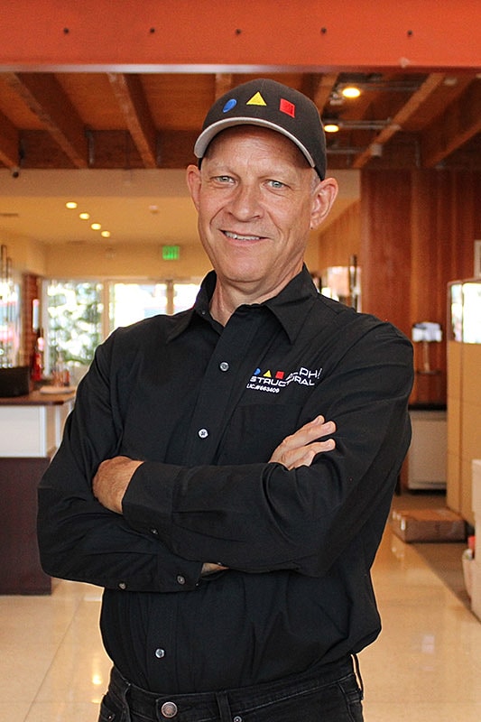 Man in black shirt smiling confidently indoors.