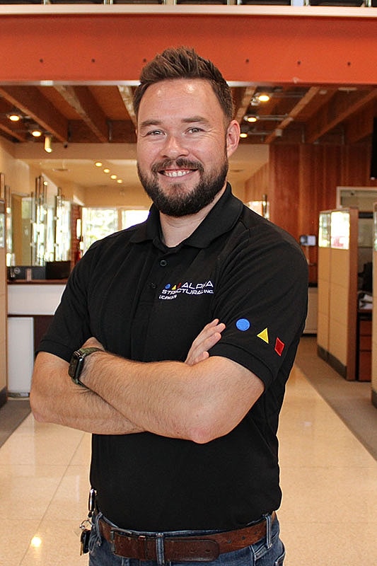Man smiling in an office with crossed arms.