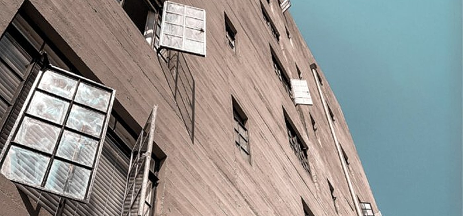 Building with window shutters against blue sky.