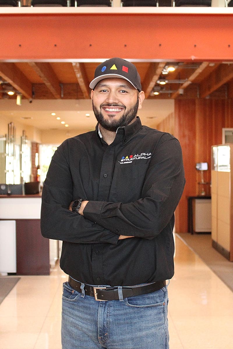 Smiling man in black shirt, office background.