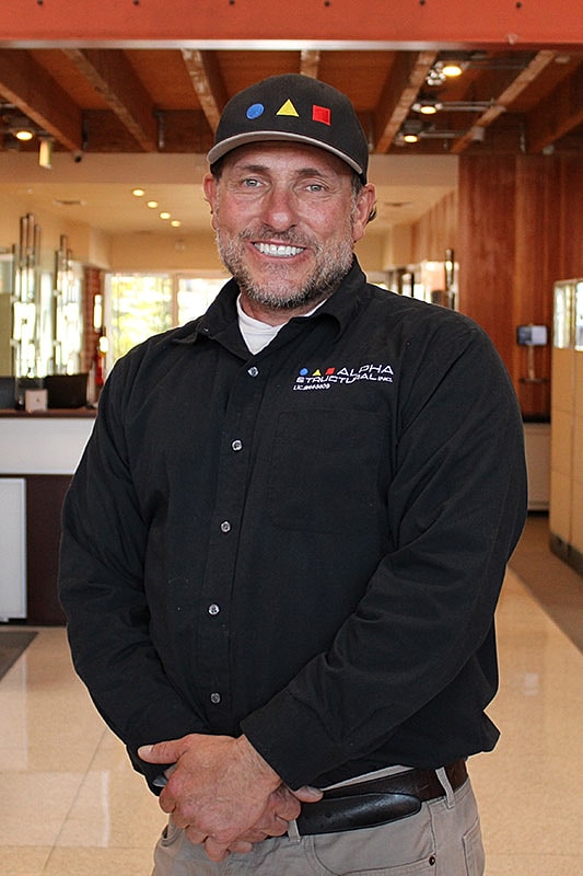 Man smiling in a black shirt indoors.