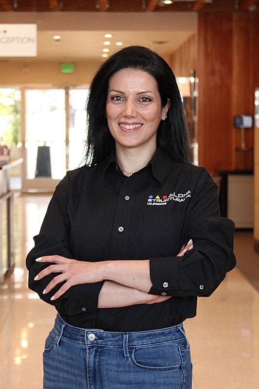 Smiling woman in official shirt with arms crossed.