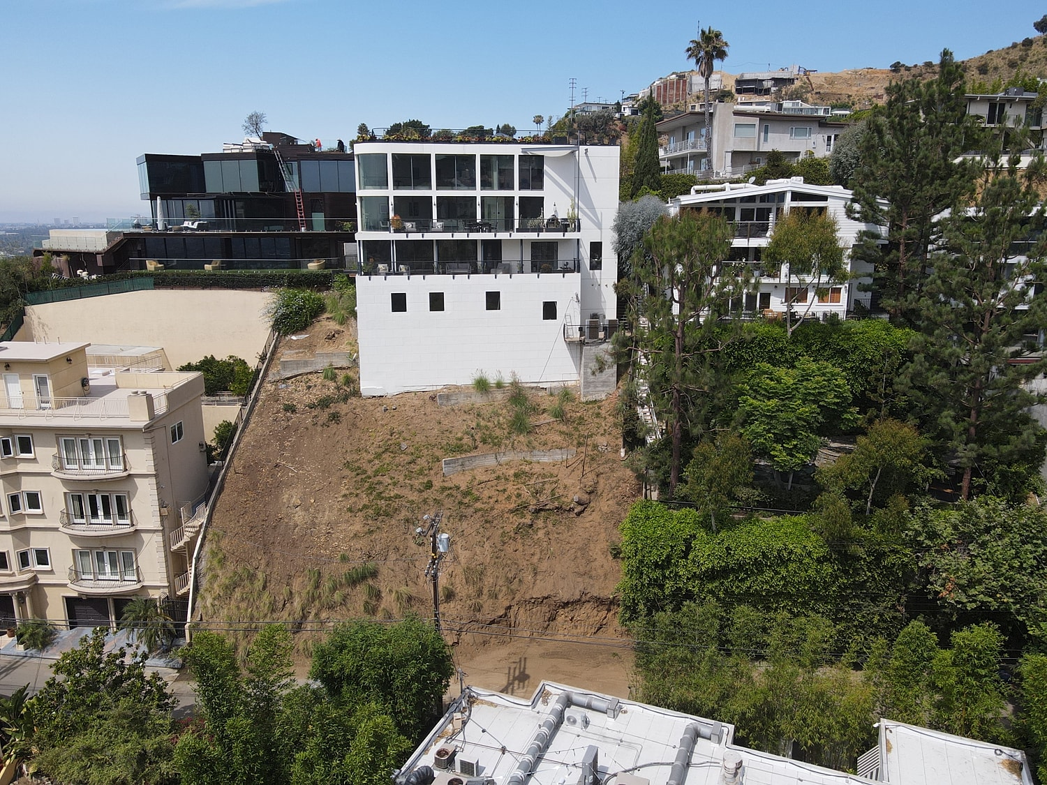 Modern homes on hillside with vegetation.