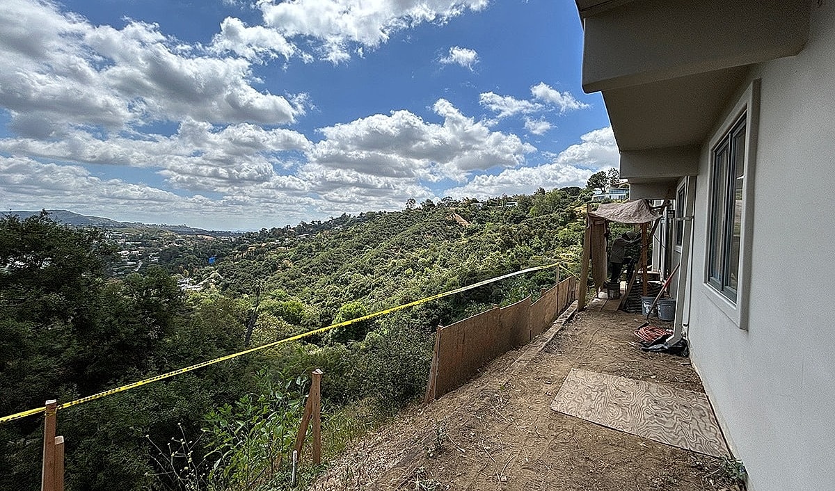 Construction site overlooking lush green hillside.