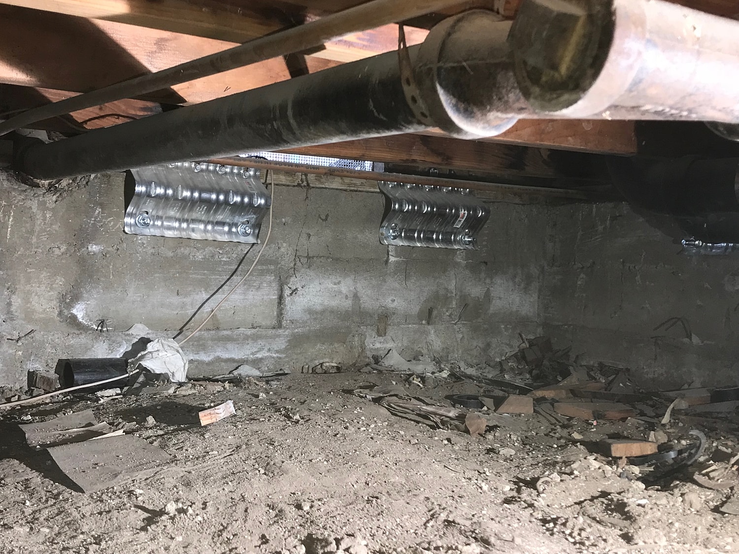 Basement interior with pipes and debris visible.