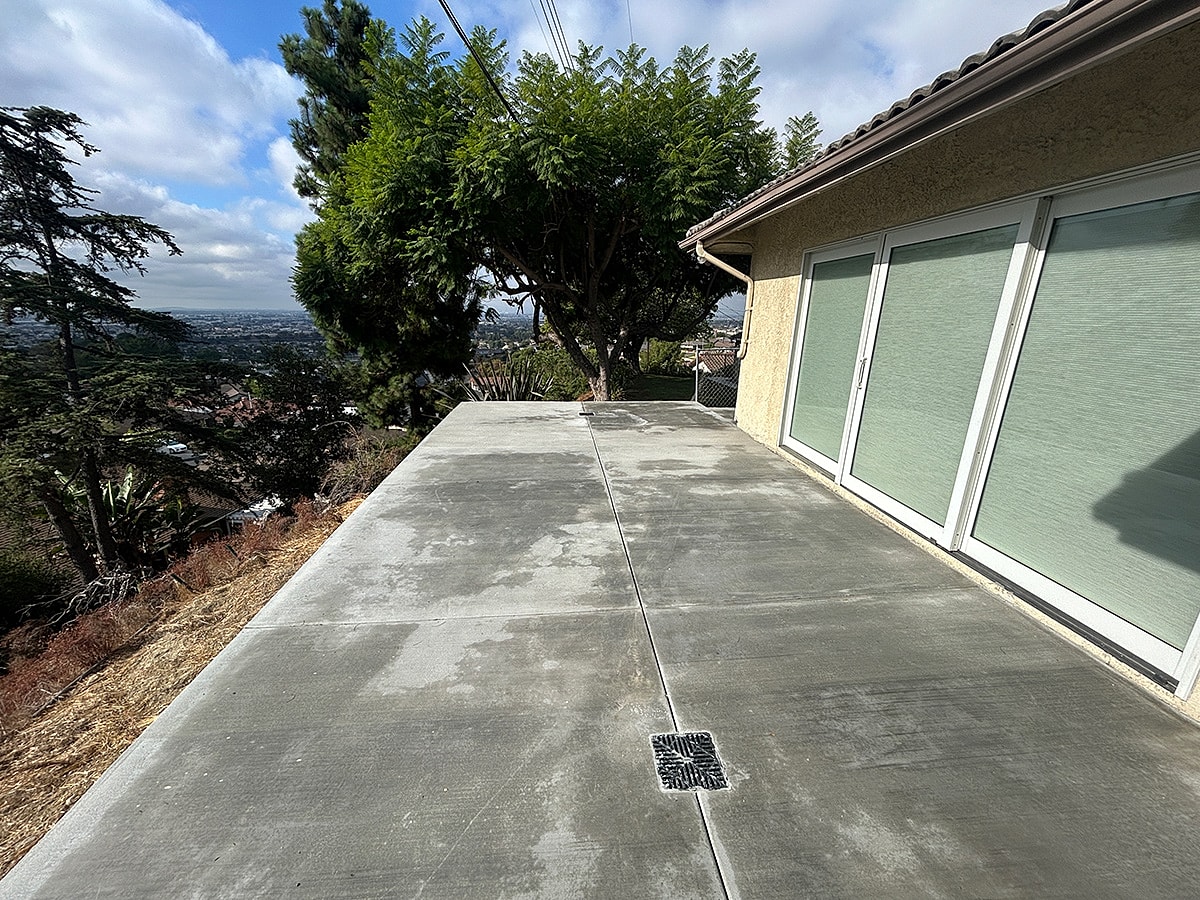 Concrete patio with hillside view and trees.