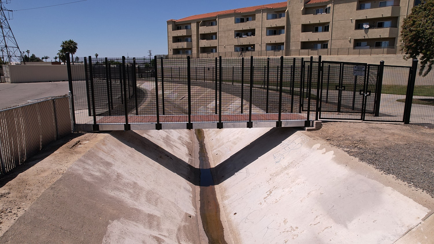 Bridge over dry canal near buildings.