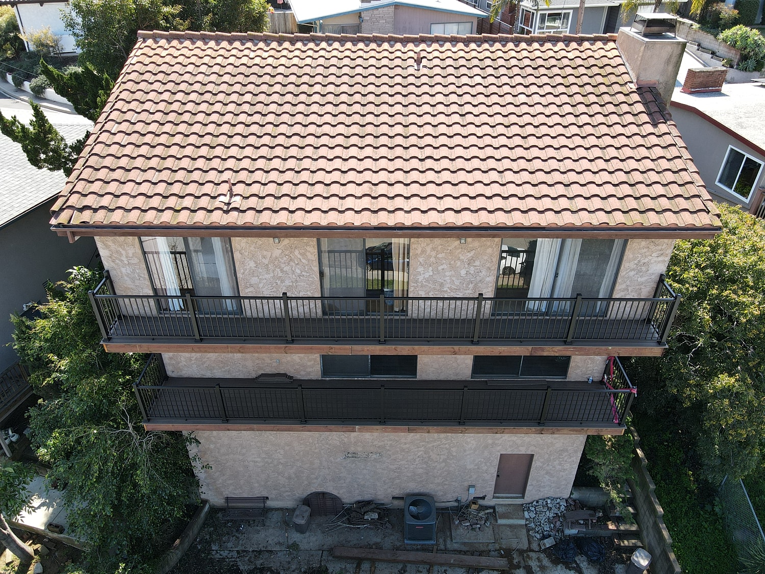 Two-story house with balconies and tiled roof.