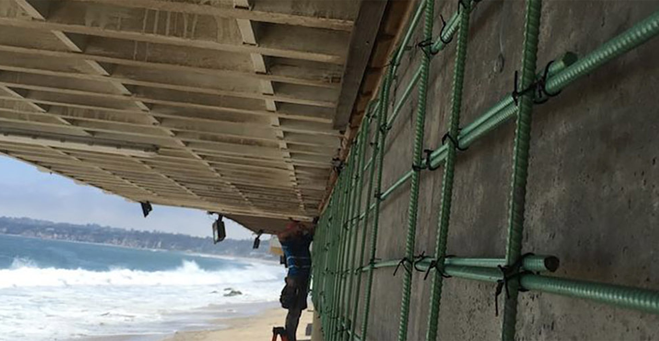 Under-construction pier above a beach landscape.