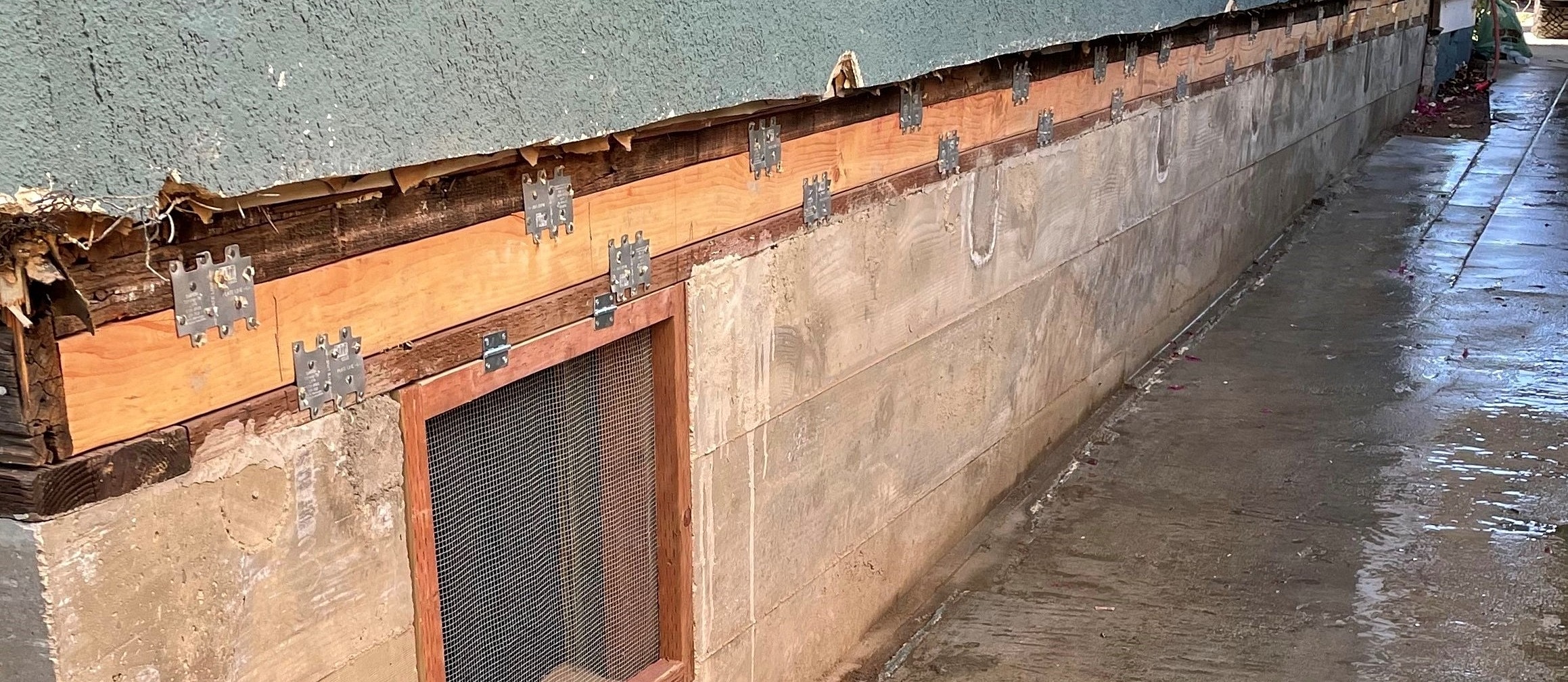 Exterior wall with wooden framing and mesh vent.