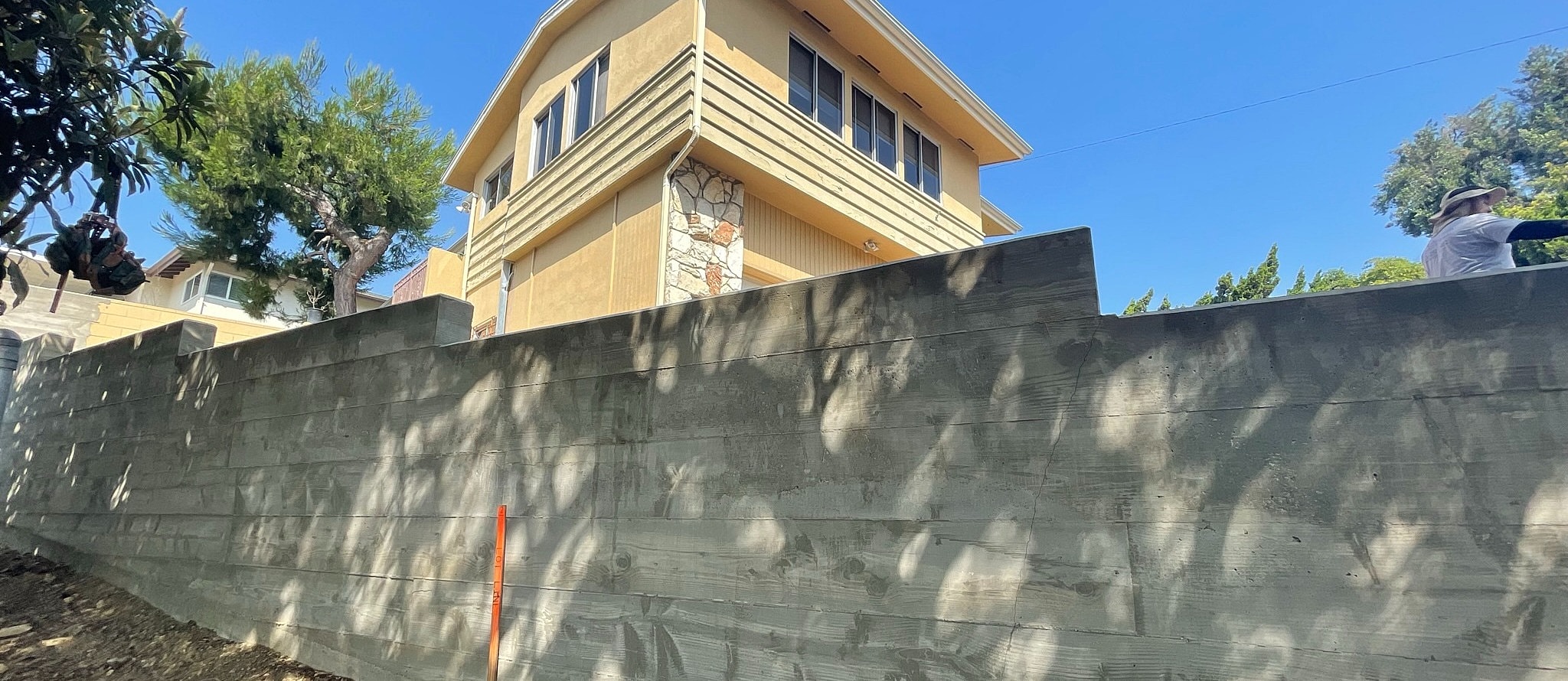 House with a tall concrete wall and trees.