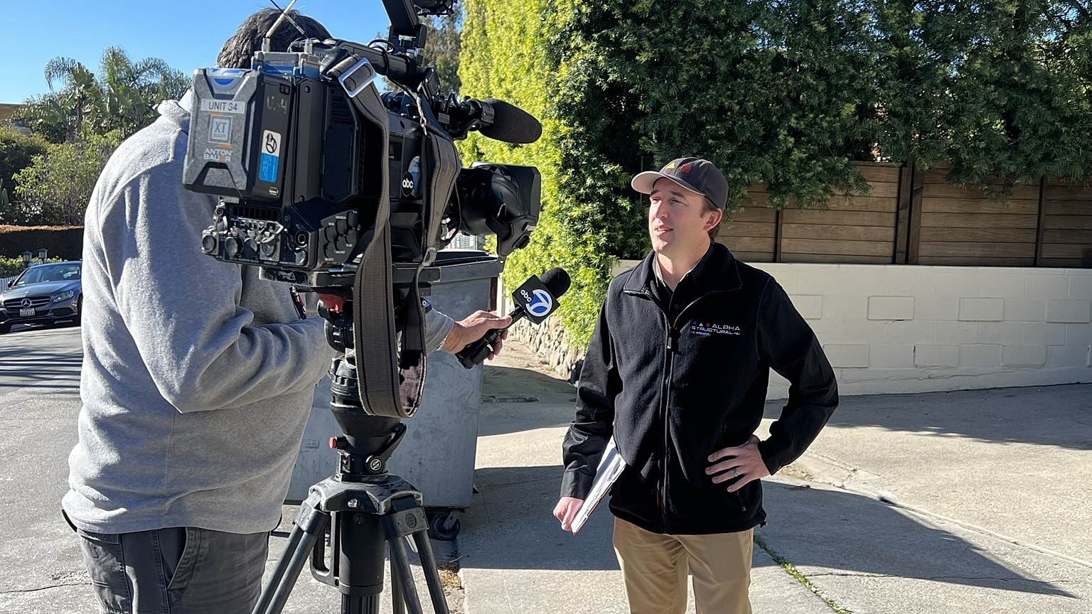 Man being interviewed by news camera crew.