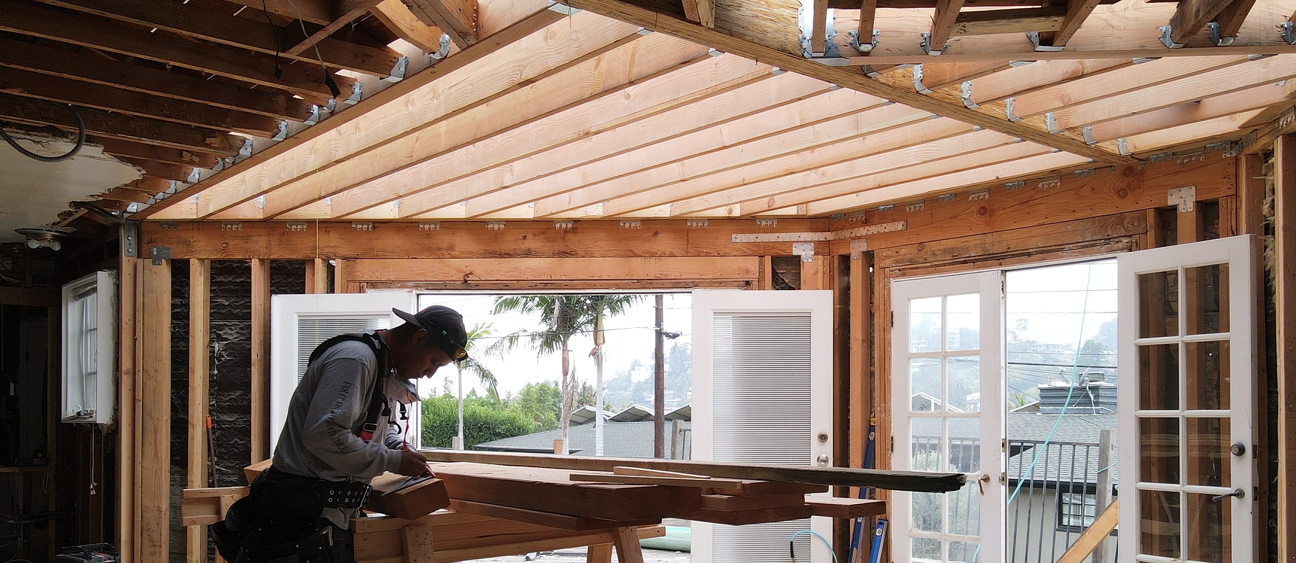Construction worker measuring wood in open space.