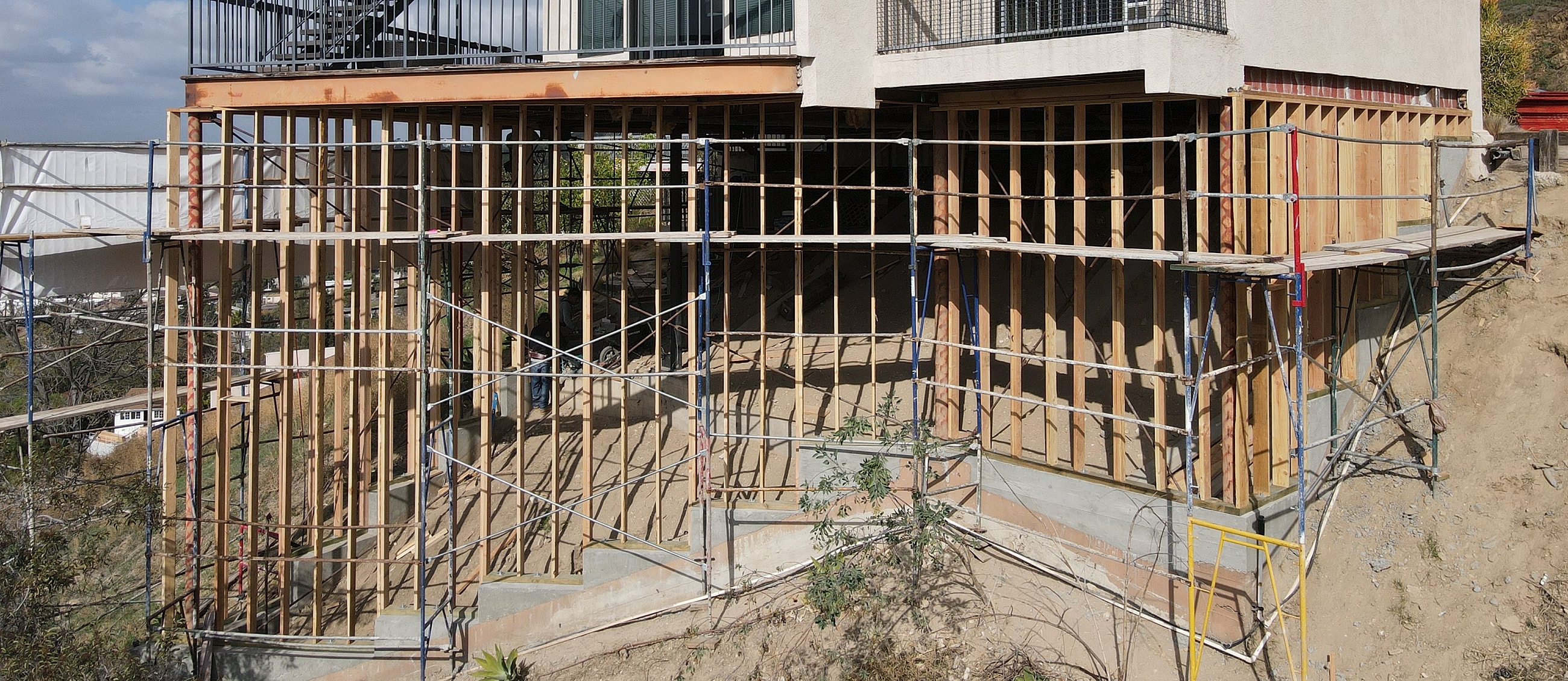 House under construction with scaffolding support.