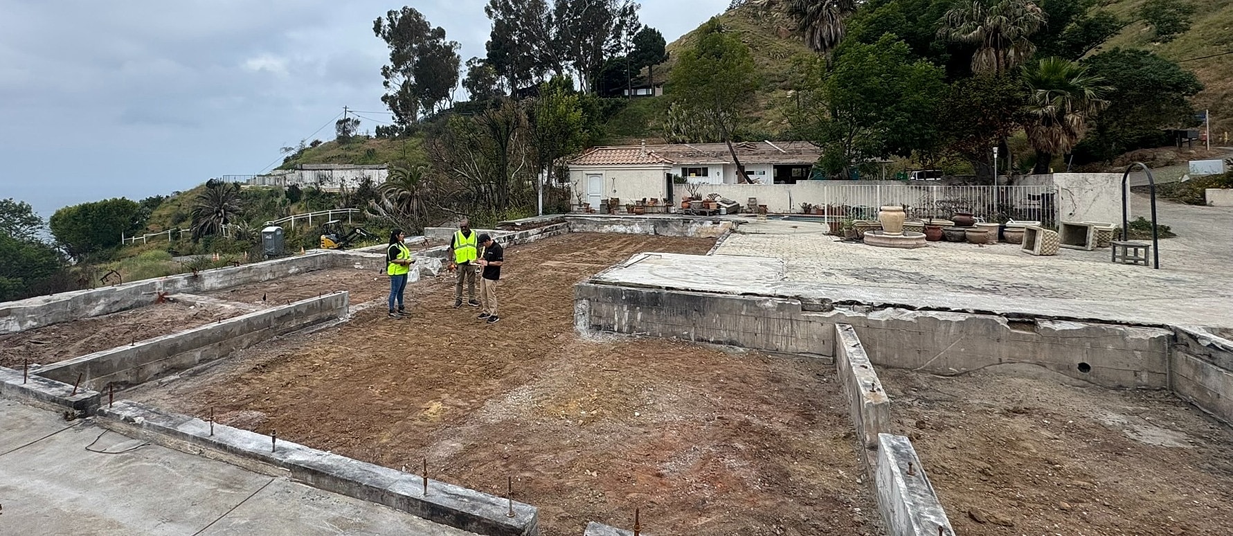 Construction site with workers and foundations visible.